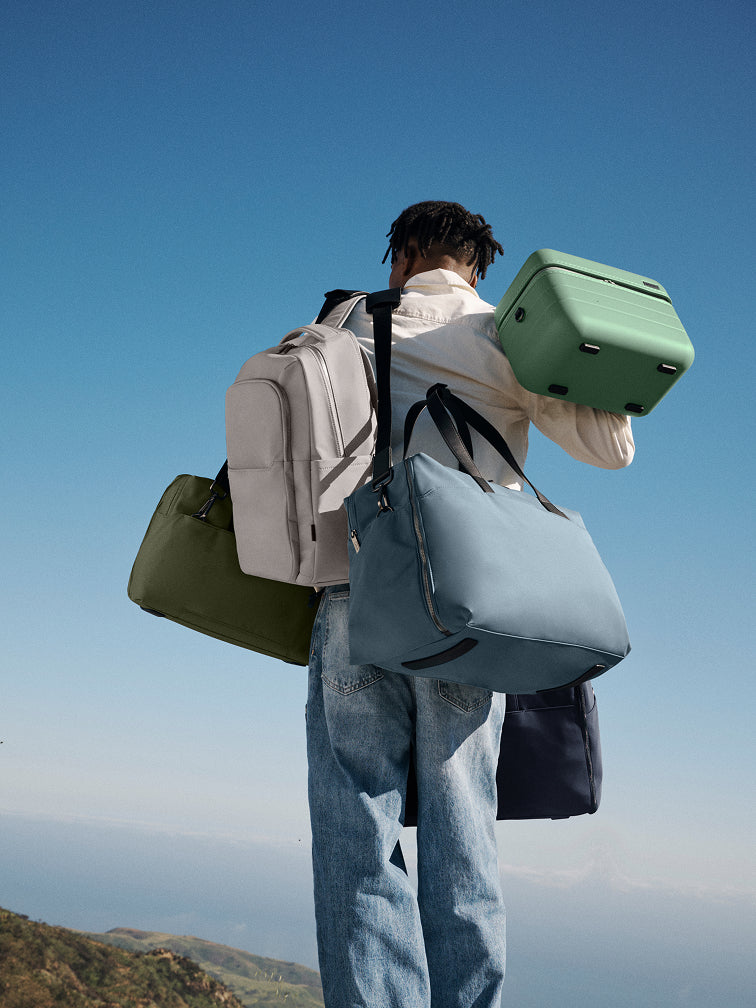 Person carrying multiple bags against a clear blue sky