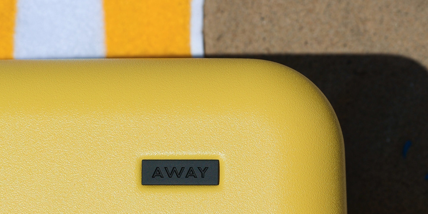 The Bigger Carry-On in Sunshine Yellow in the sun on the beach