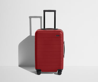 Front product view of The Carry-On suitcase in Tango Red with raised handle