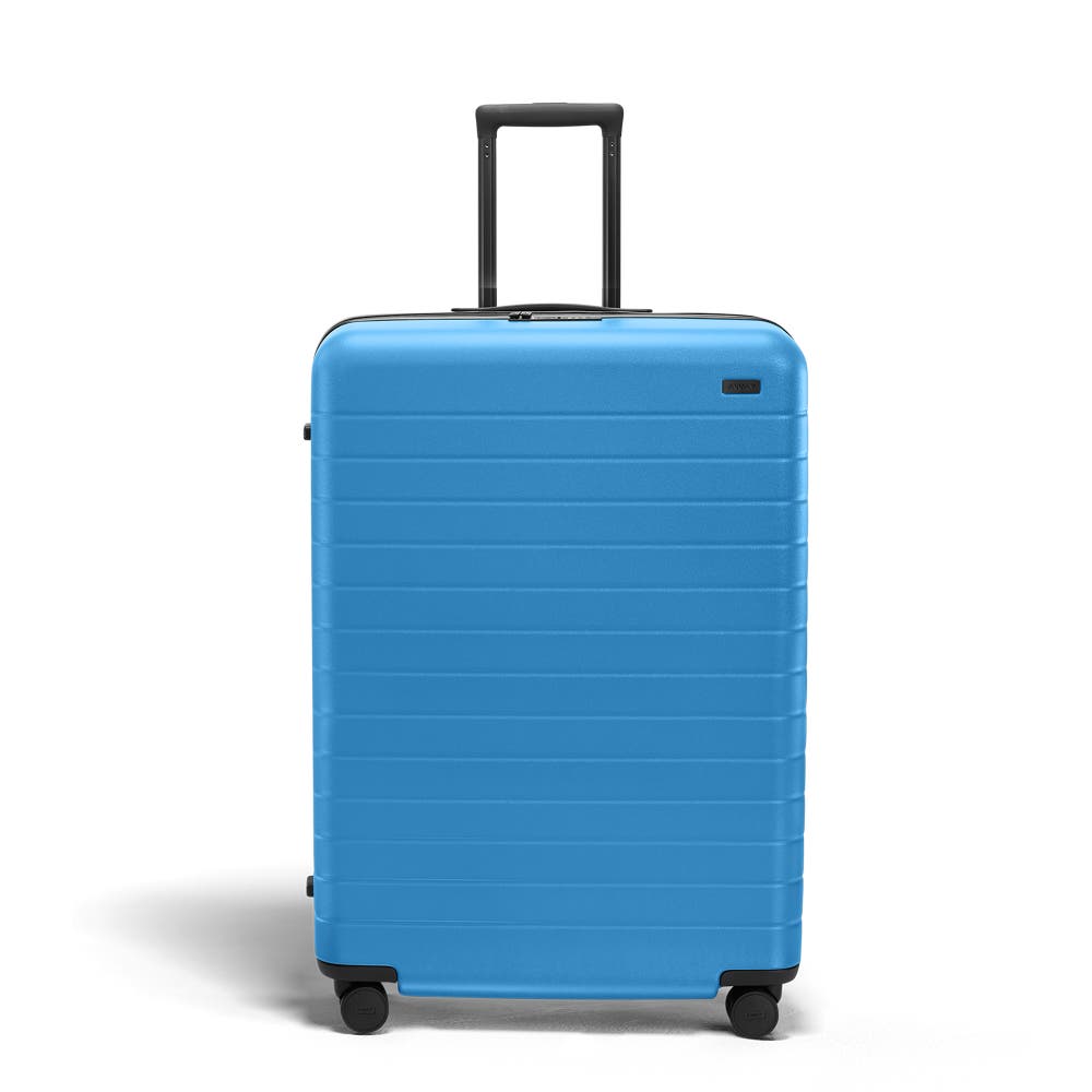 The Large Flex suitcase in Splash Blue shown open on its side and packed with Away's packing organizers to show capacity and the interior compression system, designed to help you pack more in