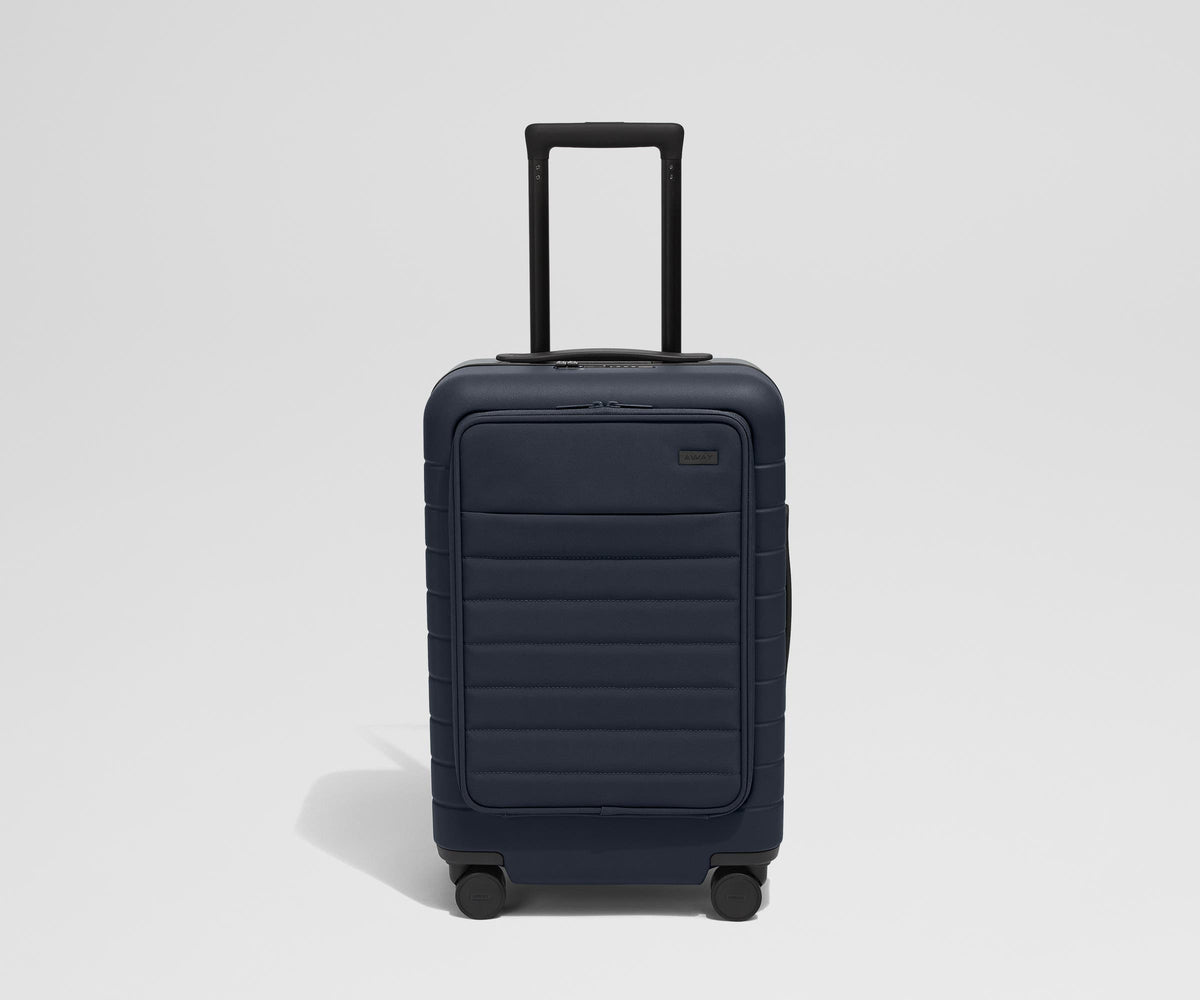 Front product view of The Front Pocket Carry-On suitcase in Navy Blue with raised handle
