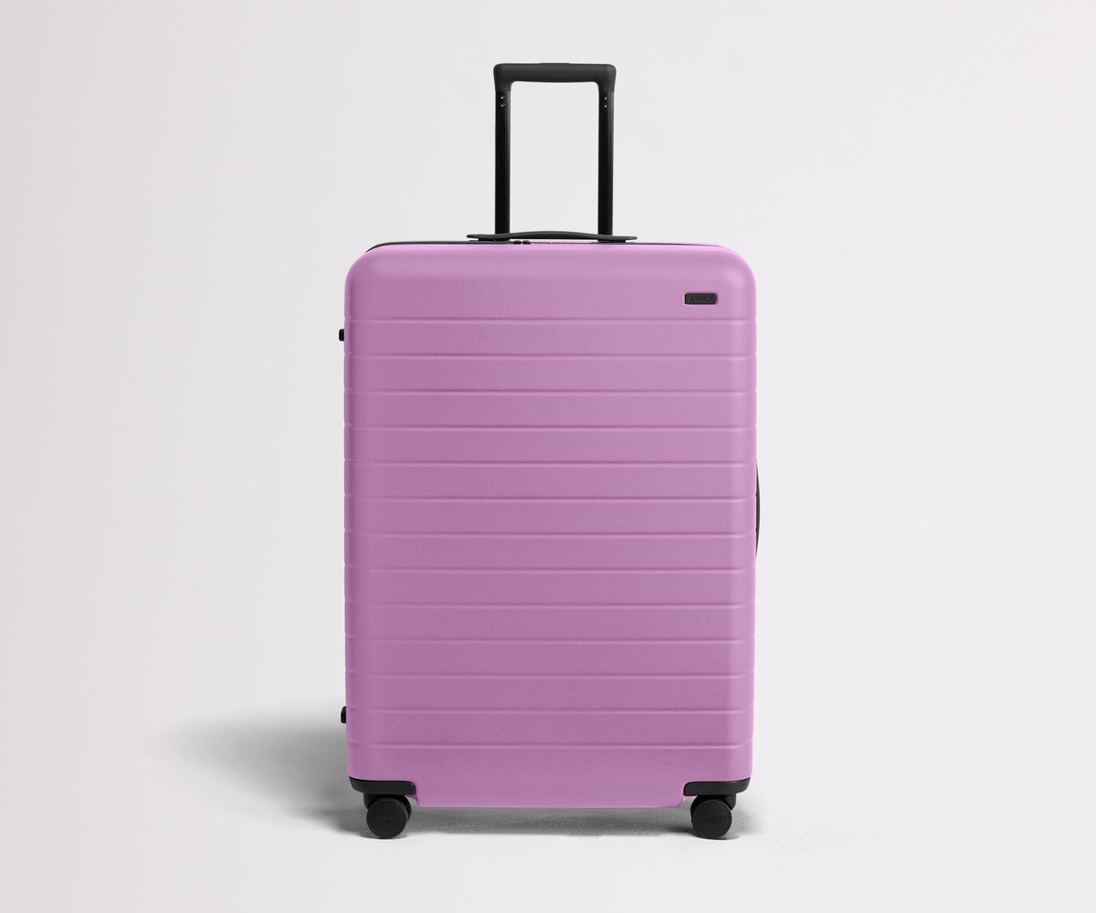 Front product view of The Large suitcase in Taffy Purple with raised handle