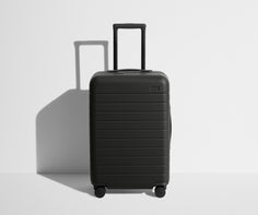 Front product view of The Bigger Carry-On suitcase in Jet Black with raised handle