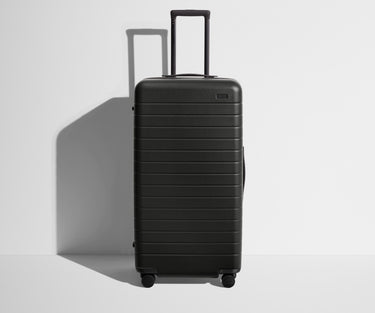 Front product view of The Trunk suitcase in Jet Black with raised handle