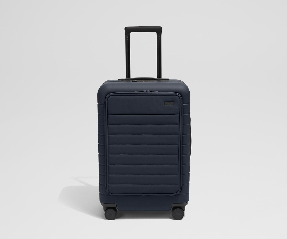 Front product view of The Front Pocket Bigger Carry-On suitcase in Navy Blue with raised handle