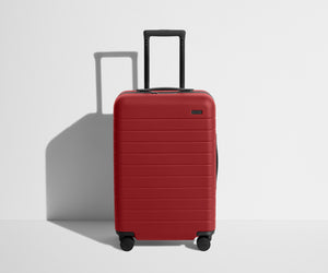 Front product view of The Bigger Carry-On suitcase in Tango Red with raised handle