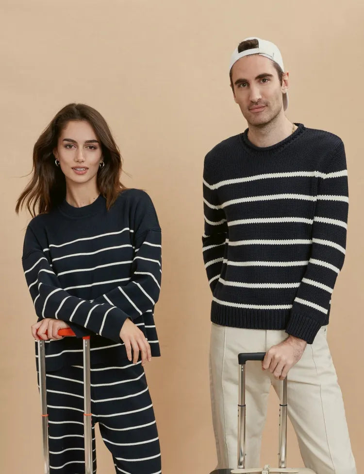 A man and woman wearing stripes standing next to two La Ligne suitcases
