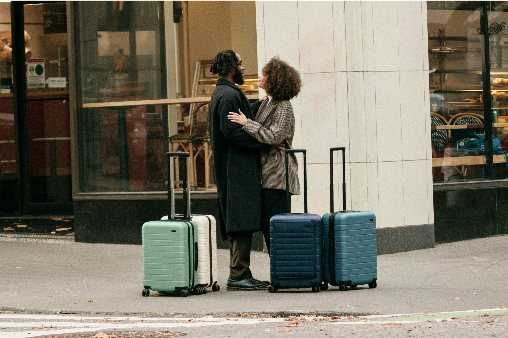 A couple embracing on the streets of Portland surrounded by 4 Away suitcases