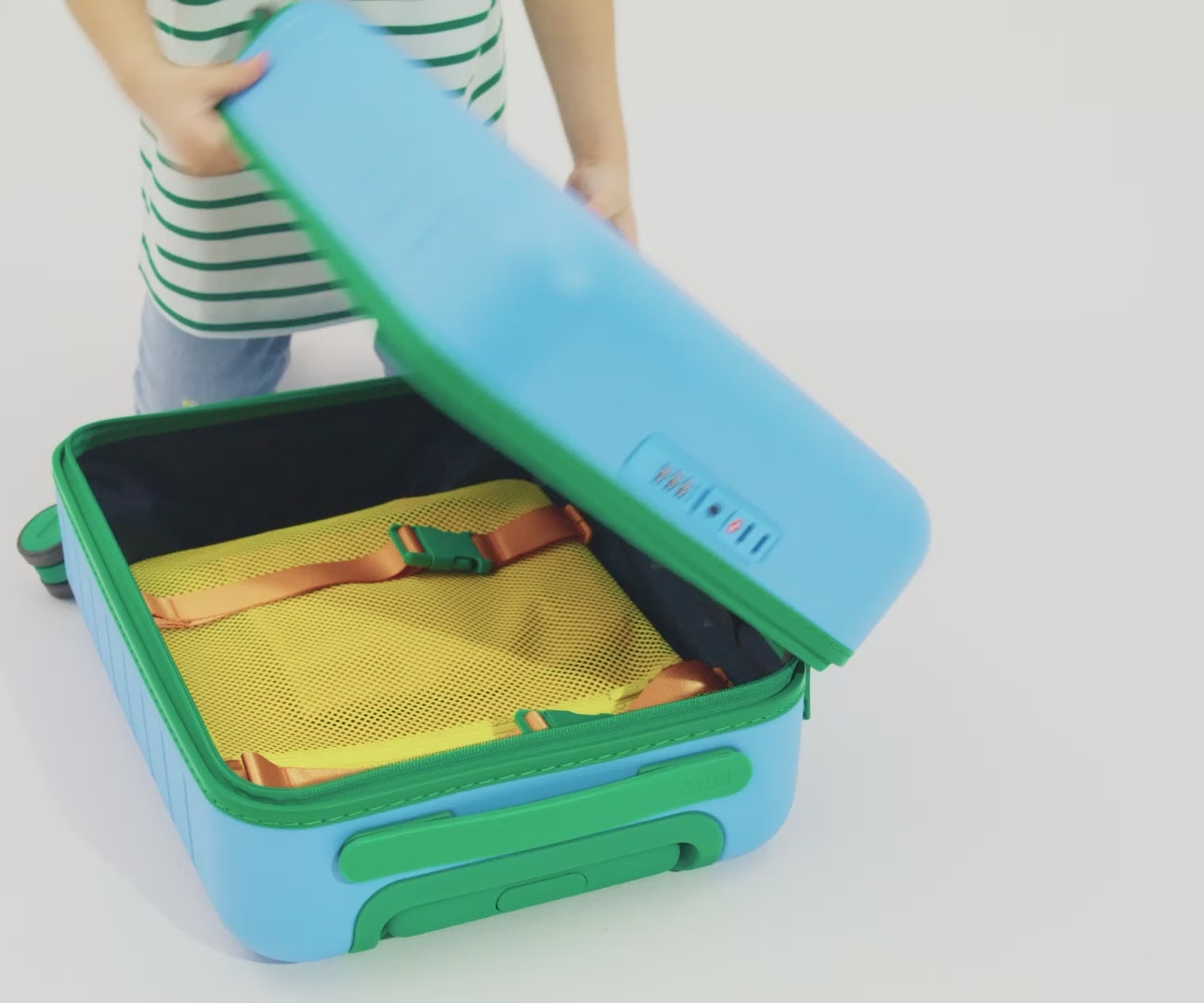 Load video: A child model filling The Kids Carry-On suitcase in Splash Blue with Away&#39;s packing organizers and using the interior organization and compression system for seamless packing